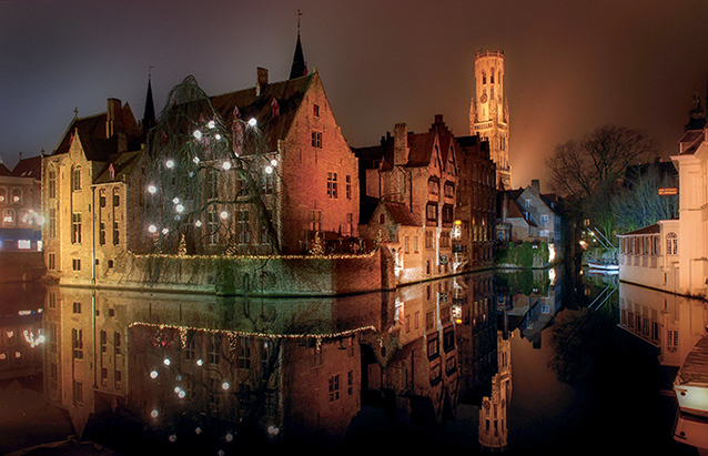 Les canaux de Bruges illuminés pour les fêtes de fin d’année. Les lumières se reflètent sur l'eau et donnent une ambiance particulière à la photo.