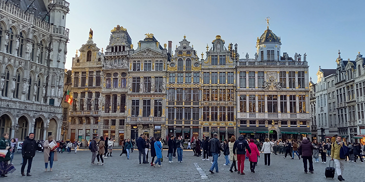 La Grand-Place de Bruxelles où des gens flânent au milieu, entourés de façade somptueusement décorées.